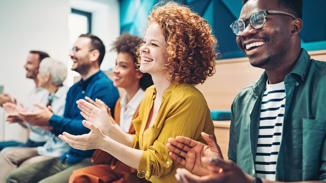 A group of people clapping in a meeting room.