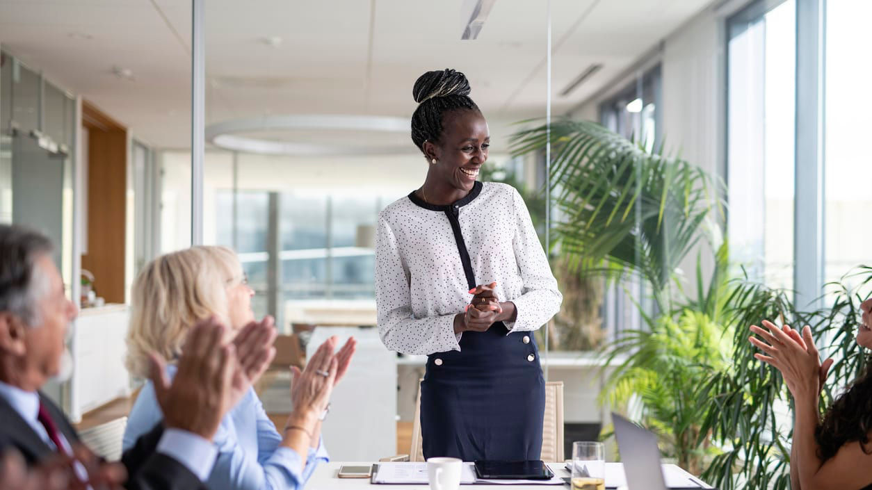 A woman in a business meeting applauding her colleagues.