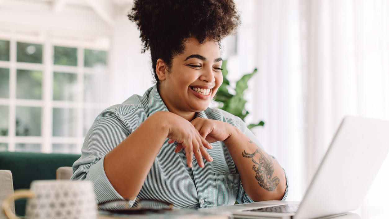 A woman smiling while working on her laptop.