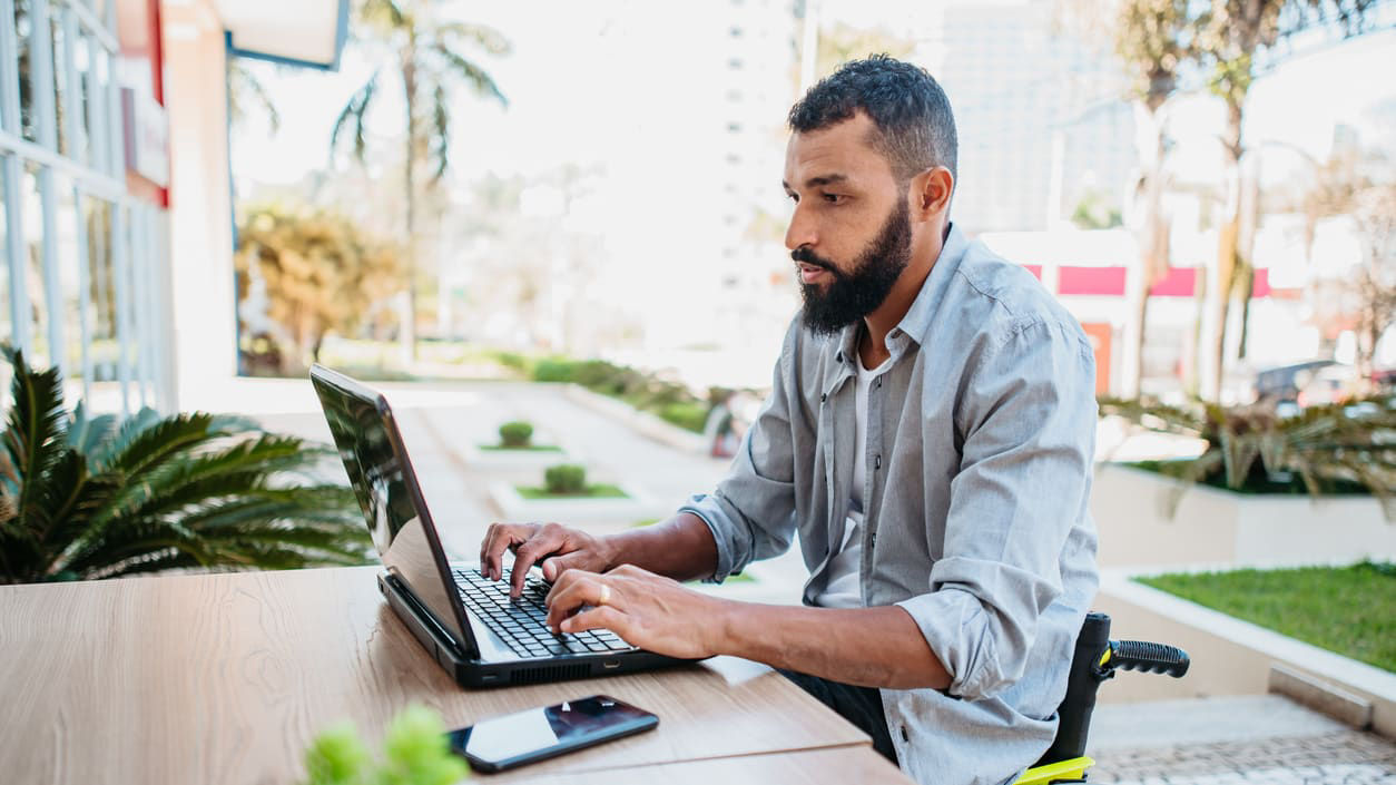 A man in a wheelchair using a laptop.