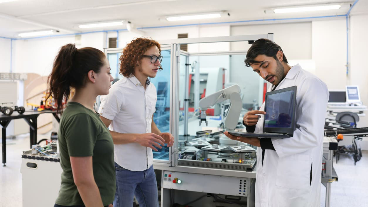 A group of people in a laboratory looking at a laptop.