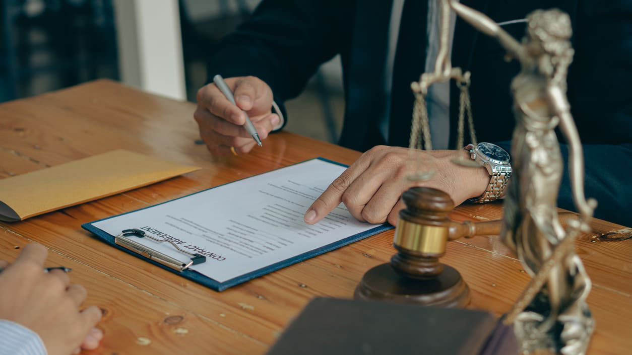 A lawyer signing a document at a desk.