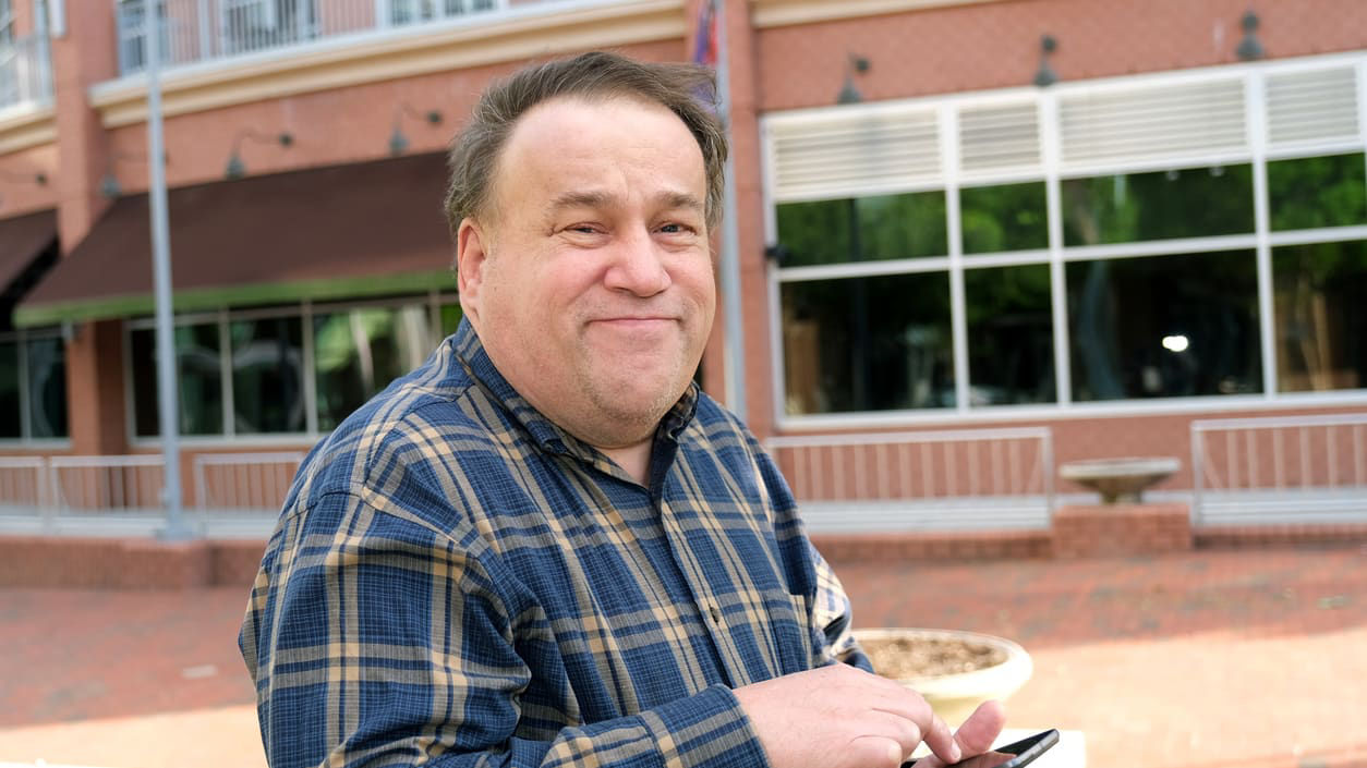 A man holding a cell phone in front of a building.