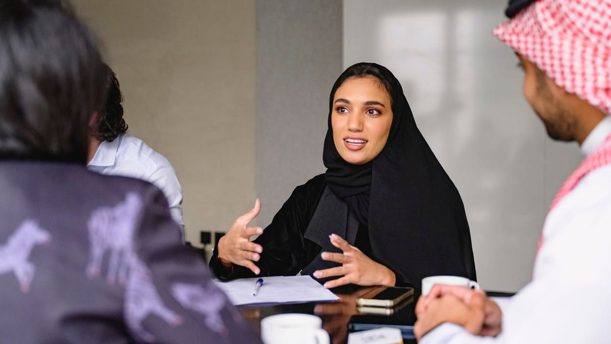 A group of people sitting around a table talking to each other.