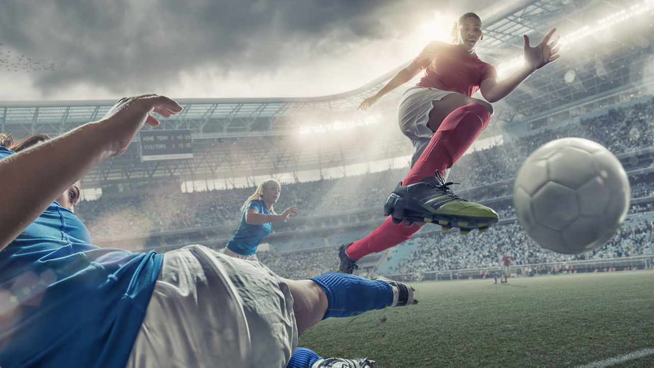 A soccer player is kicking the ball in a stadium.