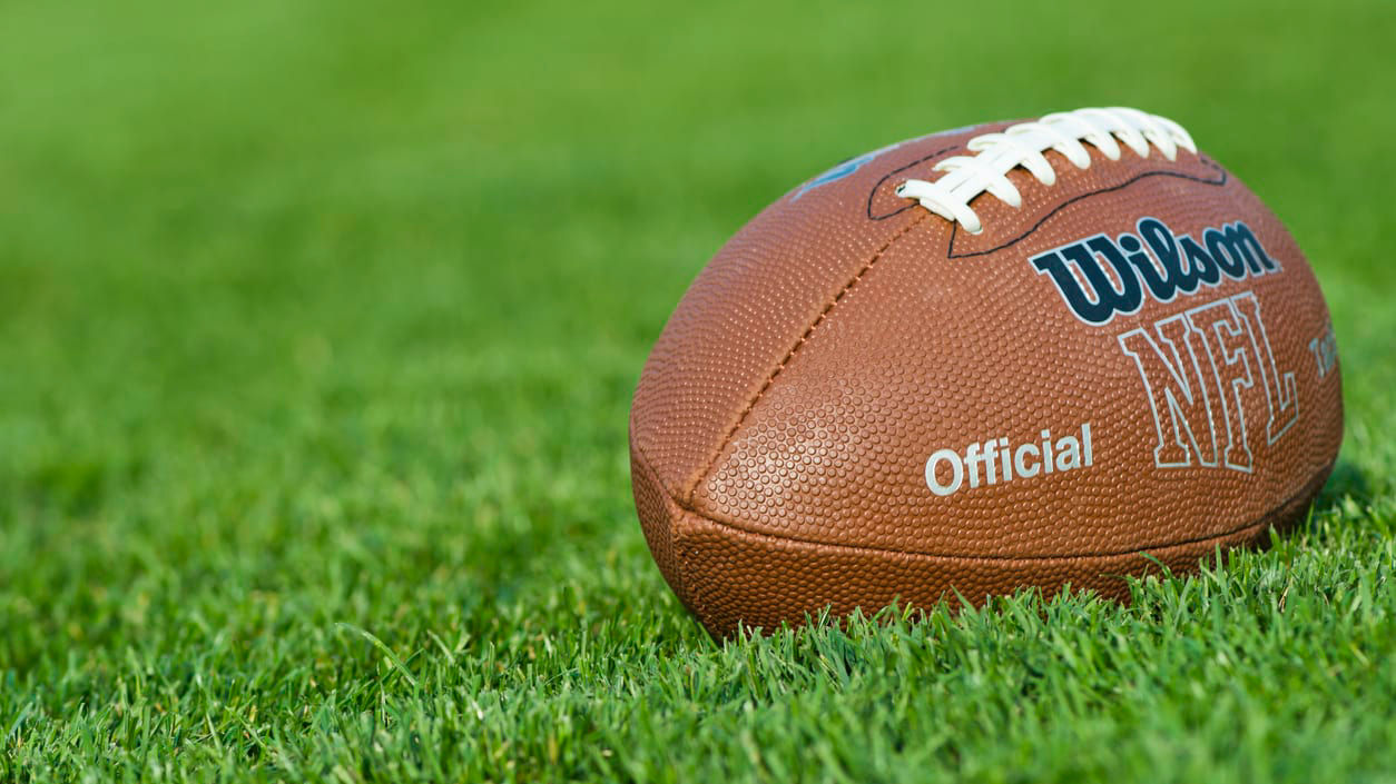 An nfl football is sitting on a green field.