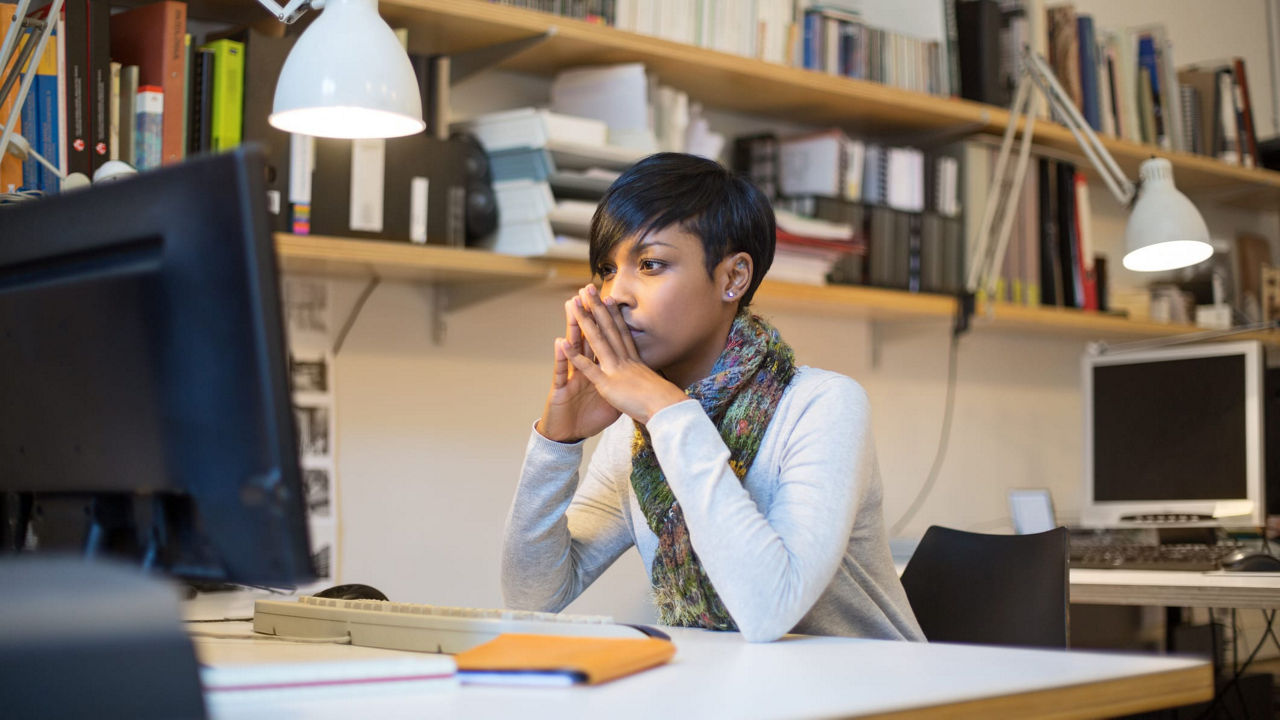 A young woman sitting at a desk with a computer in front of her.