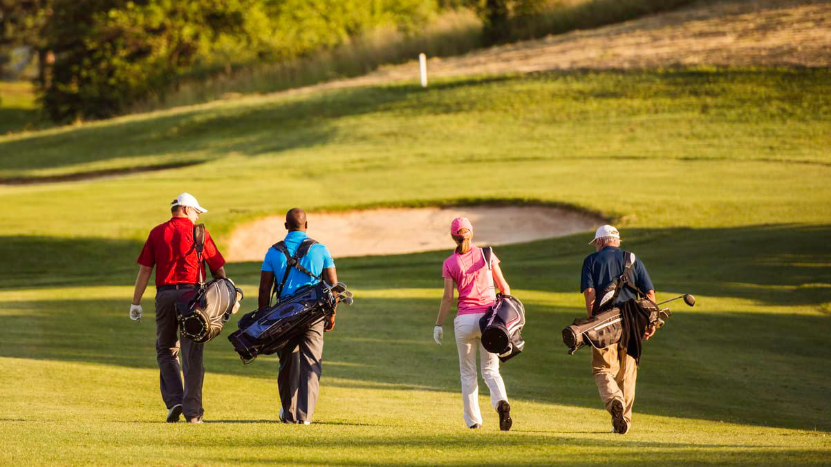 A group of people walking on a golf course.
