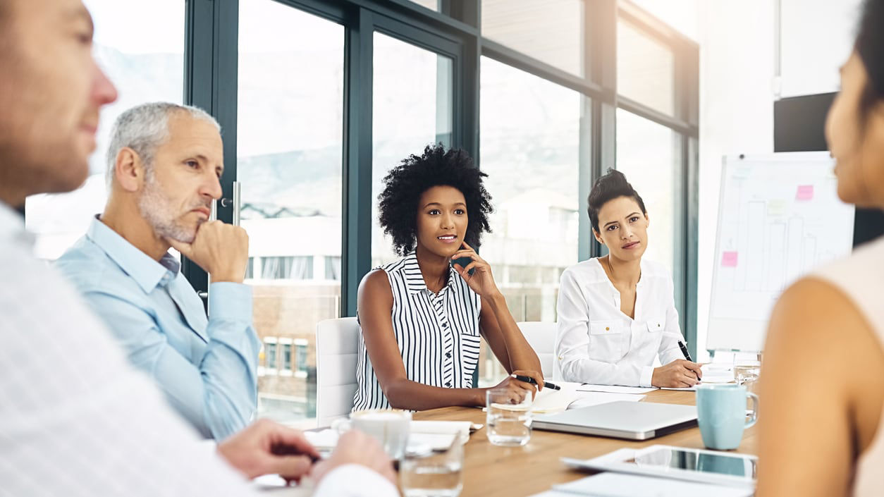 A group of people sitting around a table in a meeting.