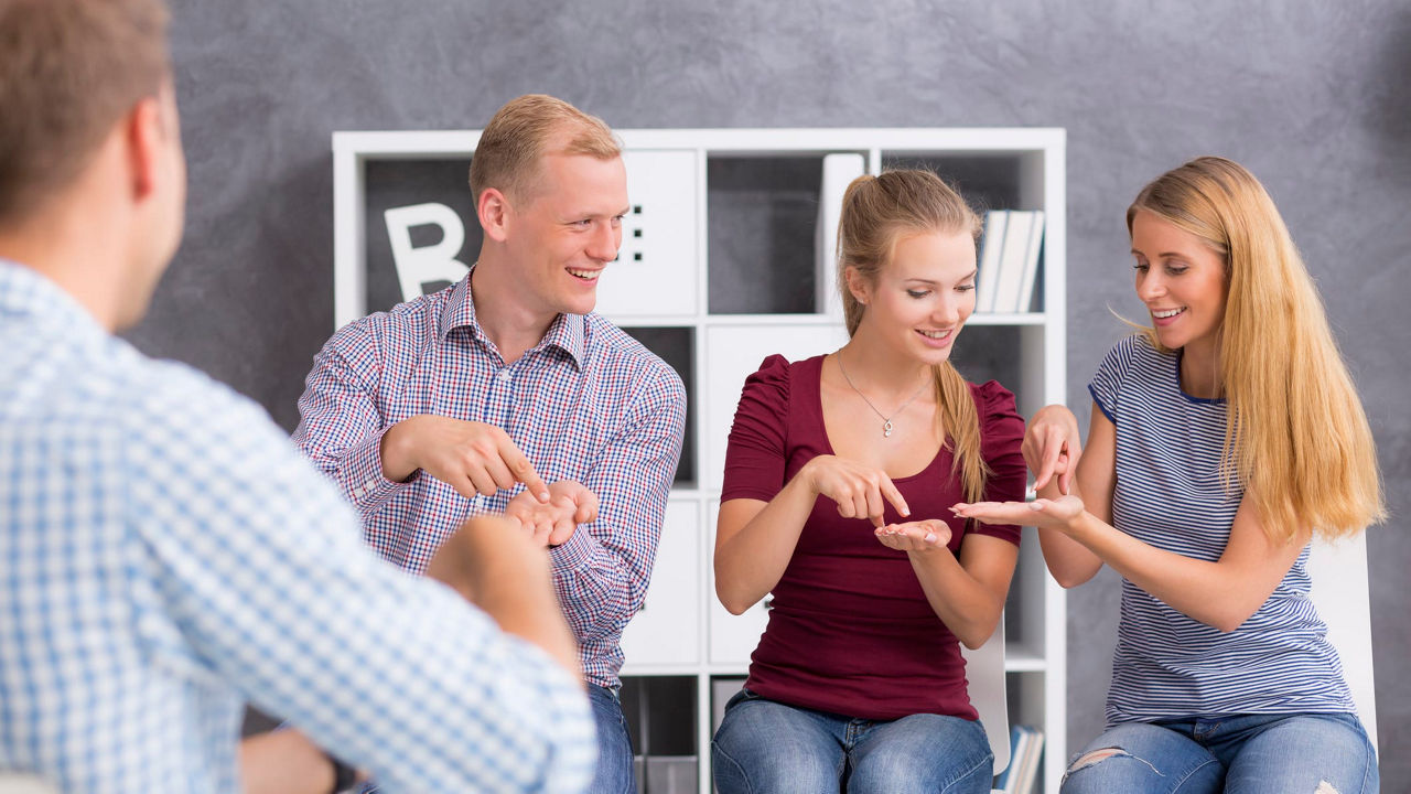 A group of people sitting in a room and playing with their phones.