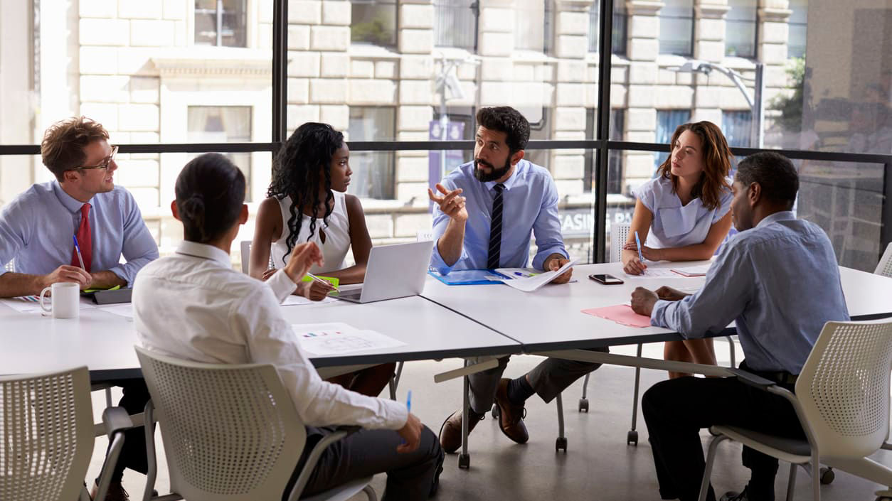 A group of people sitting around a table in a conference room.