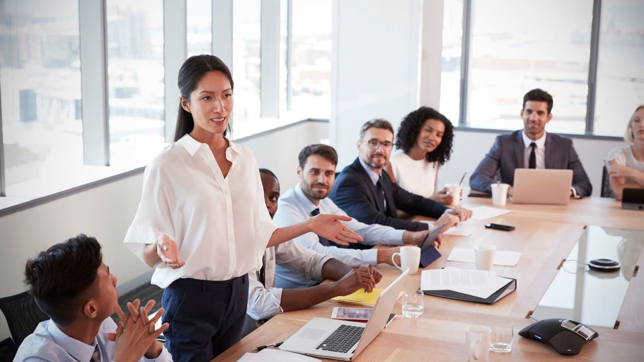 A woman is giving a presentation to a group of people at a conference table.