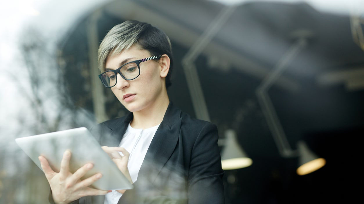 A woman in glasses is using a tablet computer.