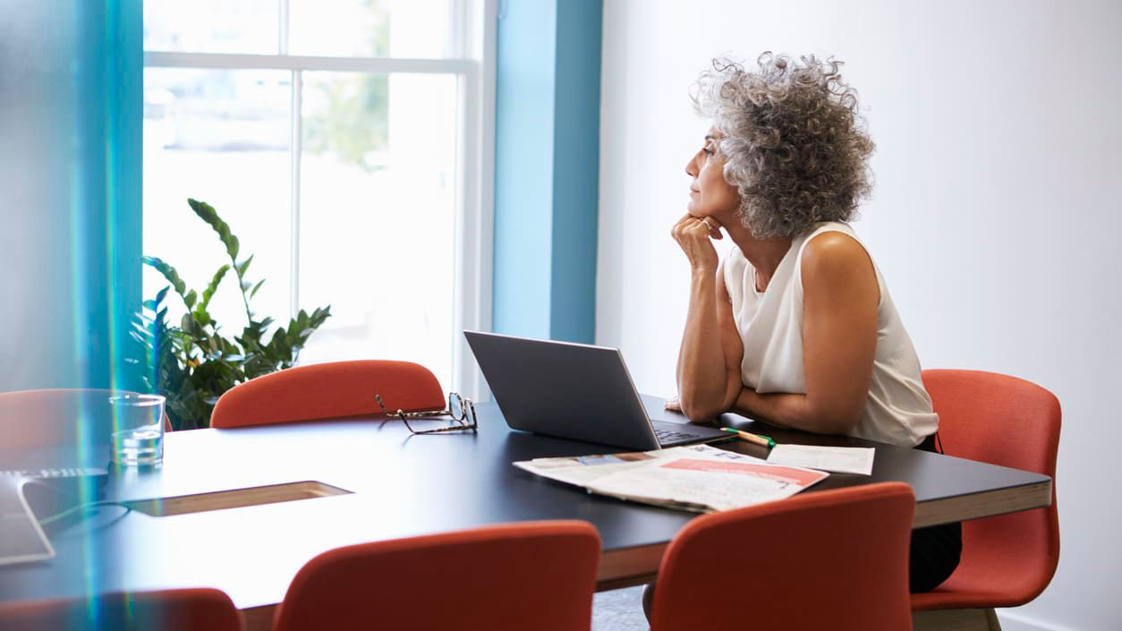 A woman sitting at a conference table looking at her laptop.