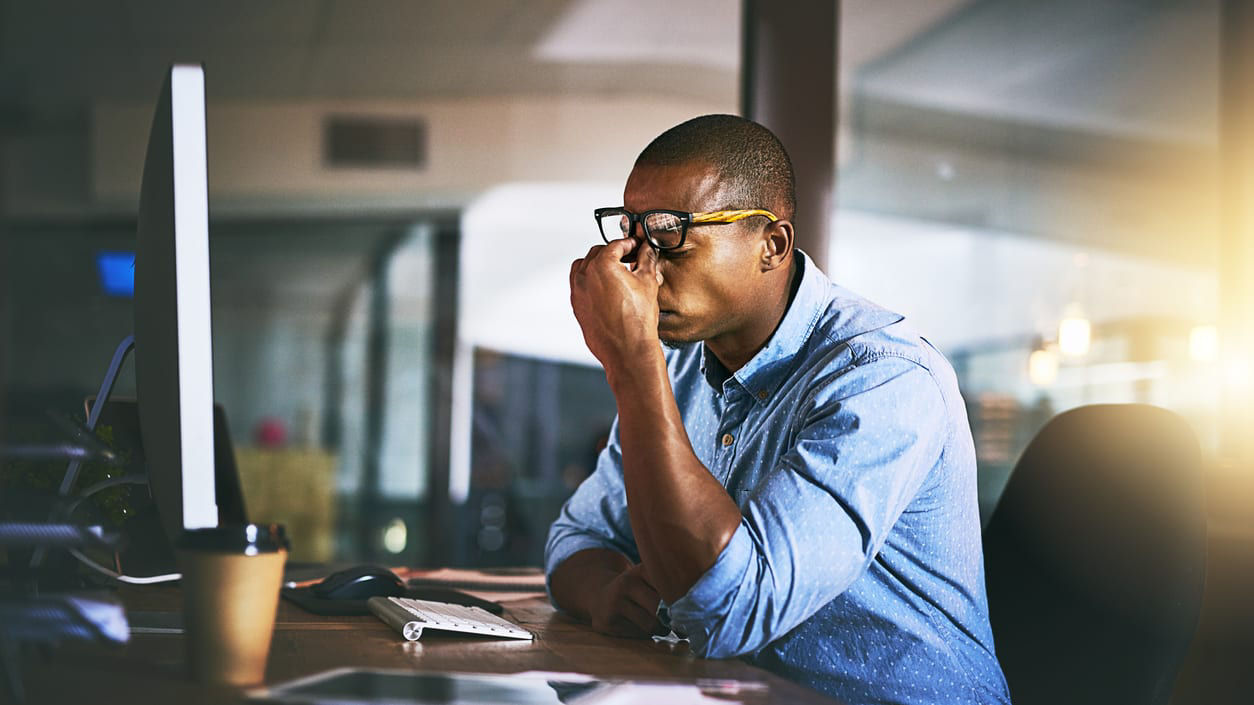 A man is sitting at a desk looking at his computer screen.