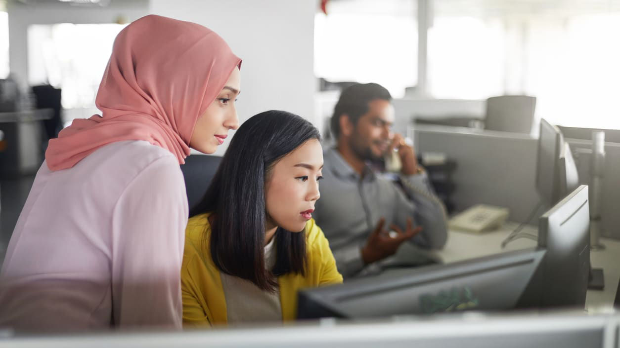 Two women looking at a computer together at work.