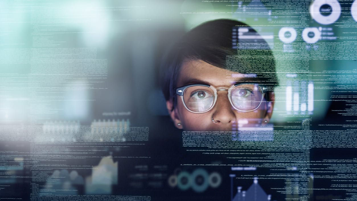 A man in glasses is looking at a computer screen.