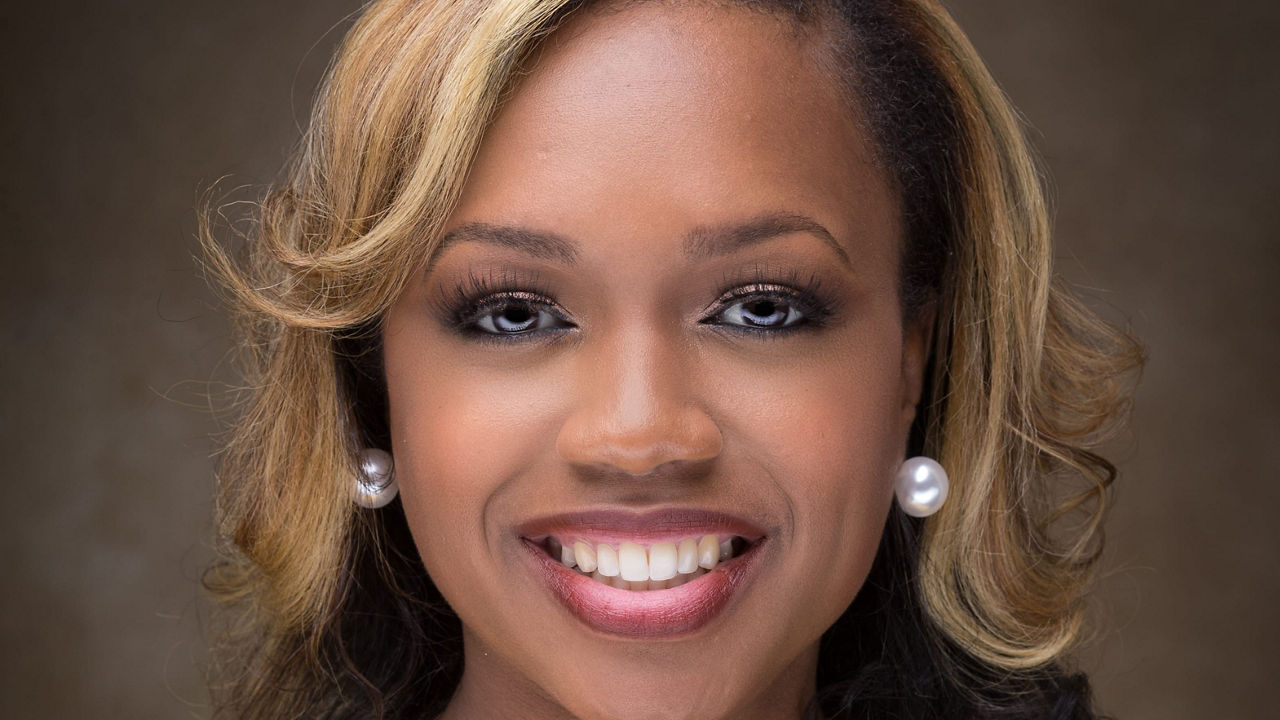 A woman smiling in a black dress.