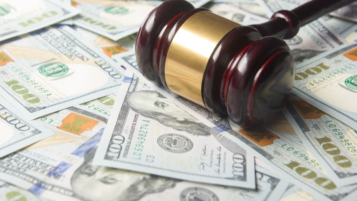 A wooden gavel on top of a pile of money.