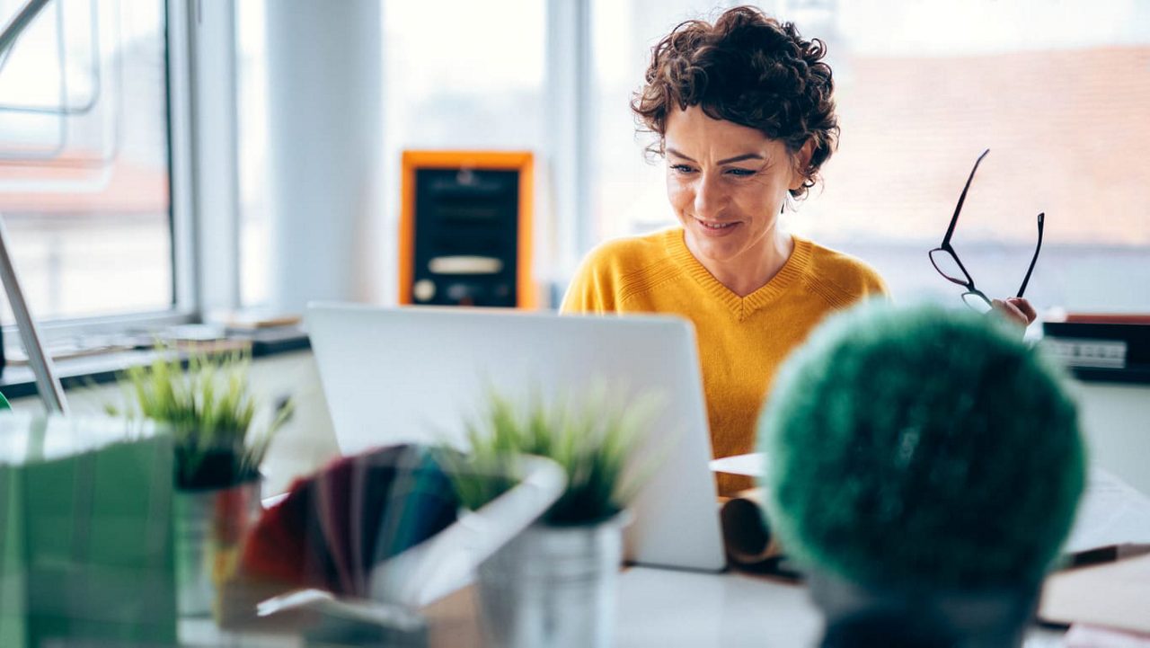 A woman working on a laptop in an office.