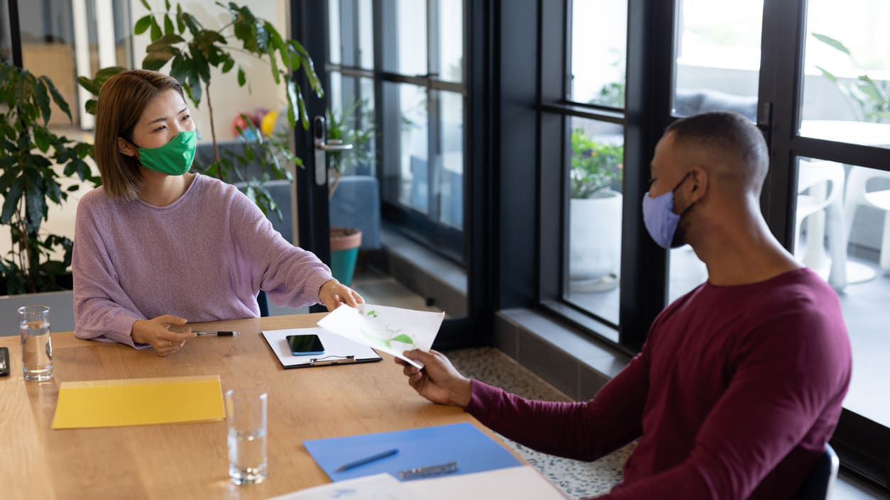 A group of people wearing face masks at a conference table.