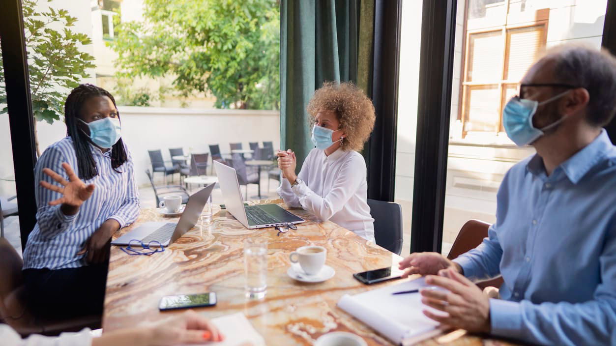 A group of people wearing face masks at a table.