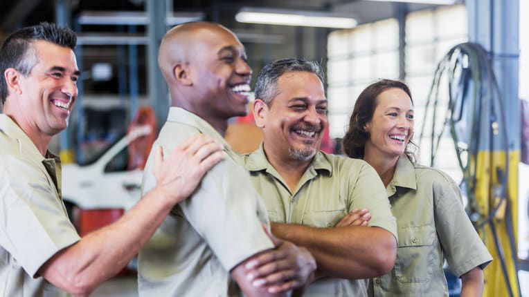 A group of mechanics smiling in a garage.