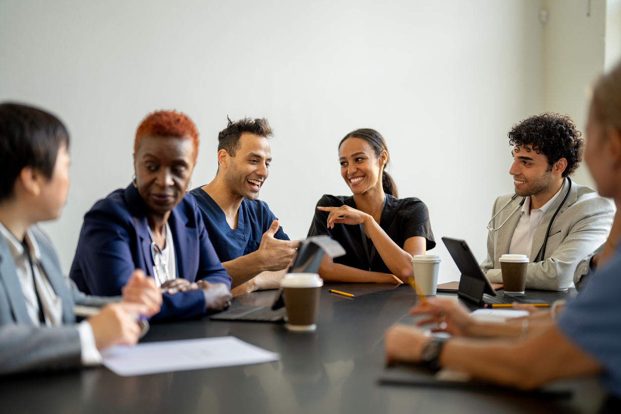 A multicultural team of professionals sharing ideas around a conference table, fostering collaboration and open communication in a positive workspace. Depicts teamwork, diversity, and dedication to shared goals.