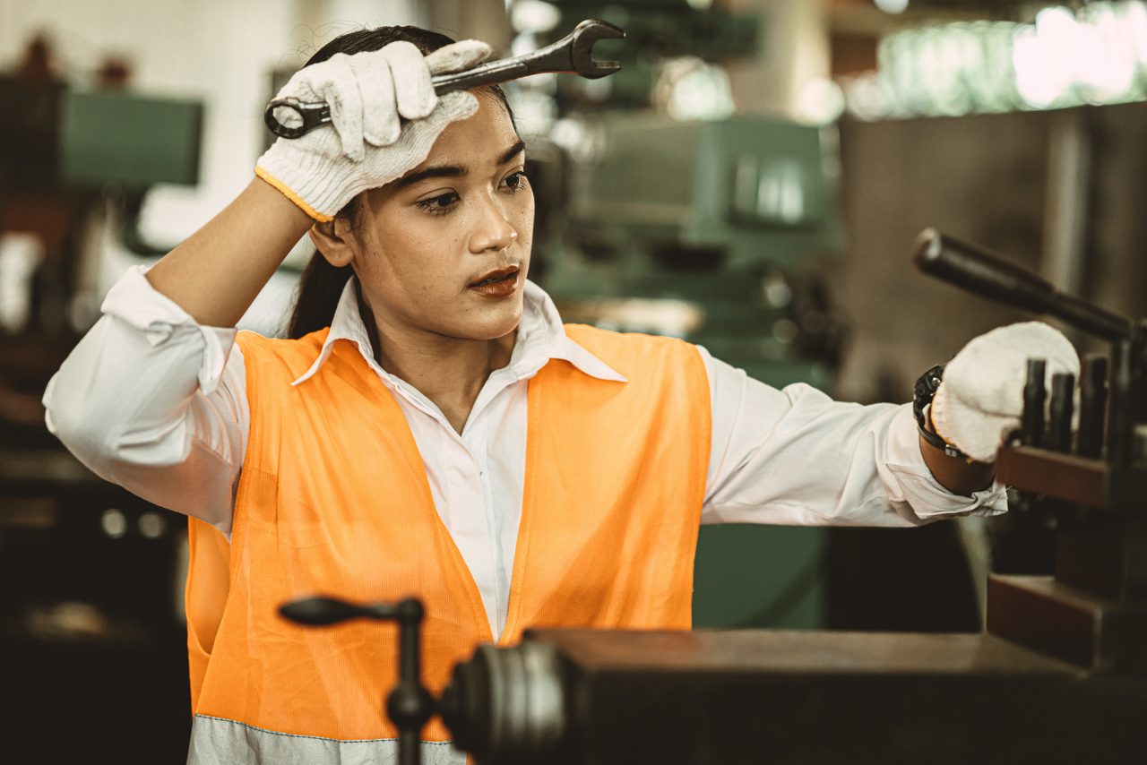 An employee working in a hot indoor manufacturing workplace with tools.