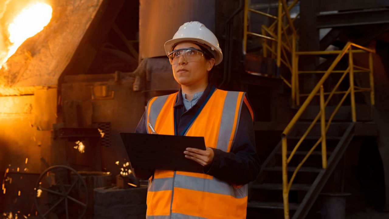 A worker at a steel factory holding a clipboard.