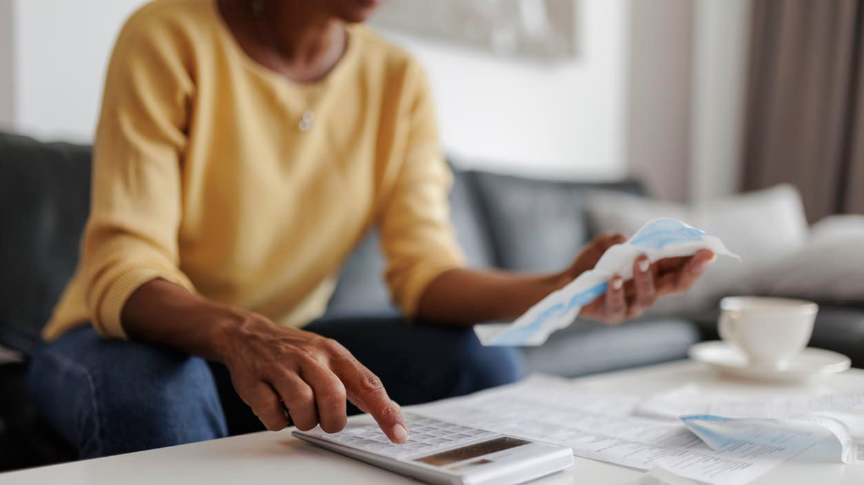 A woman sitting on a couch with a calculator and papers.