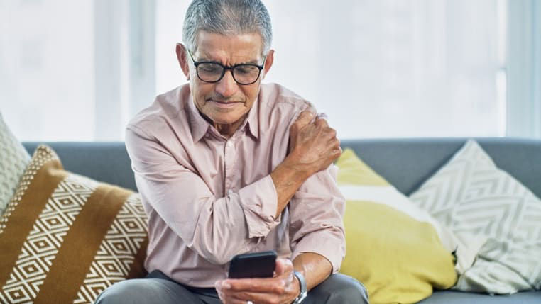 A man sitting on a couch with a cell phone in his hand.