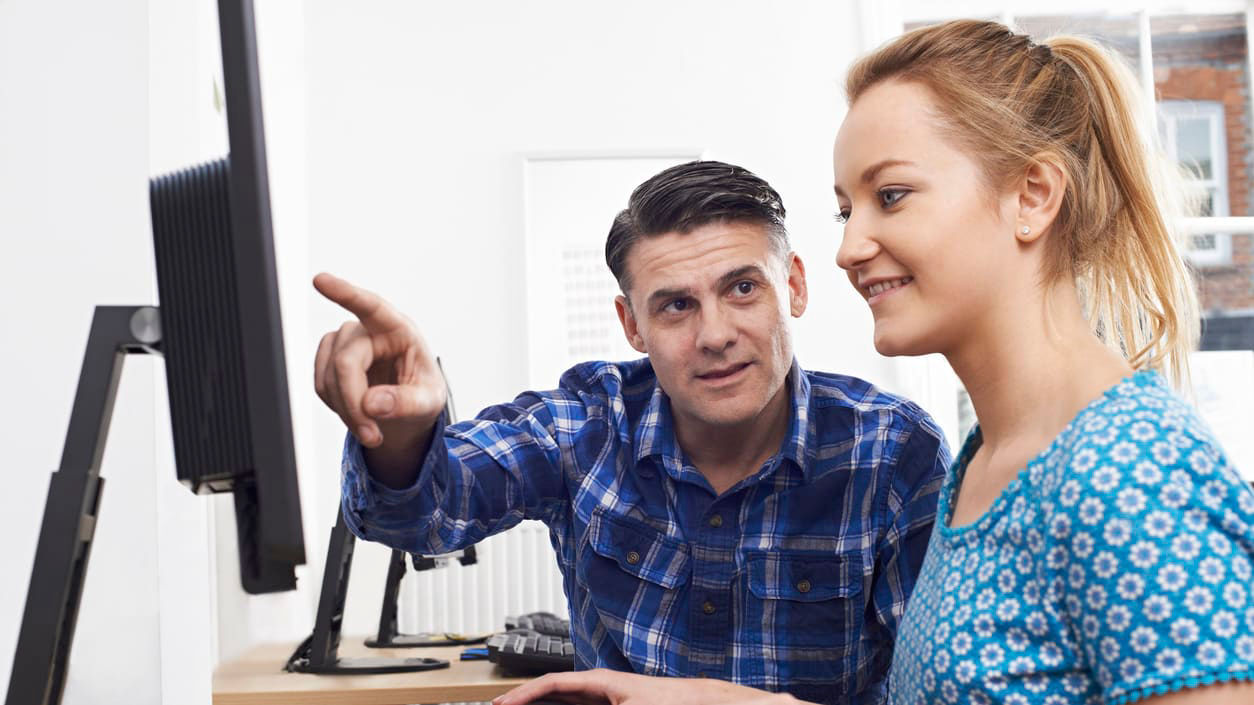 A man and a woman sitting in front of a computer.