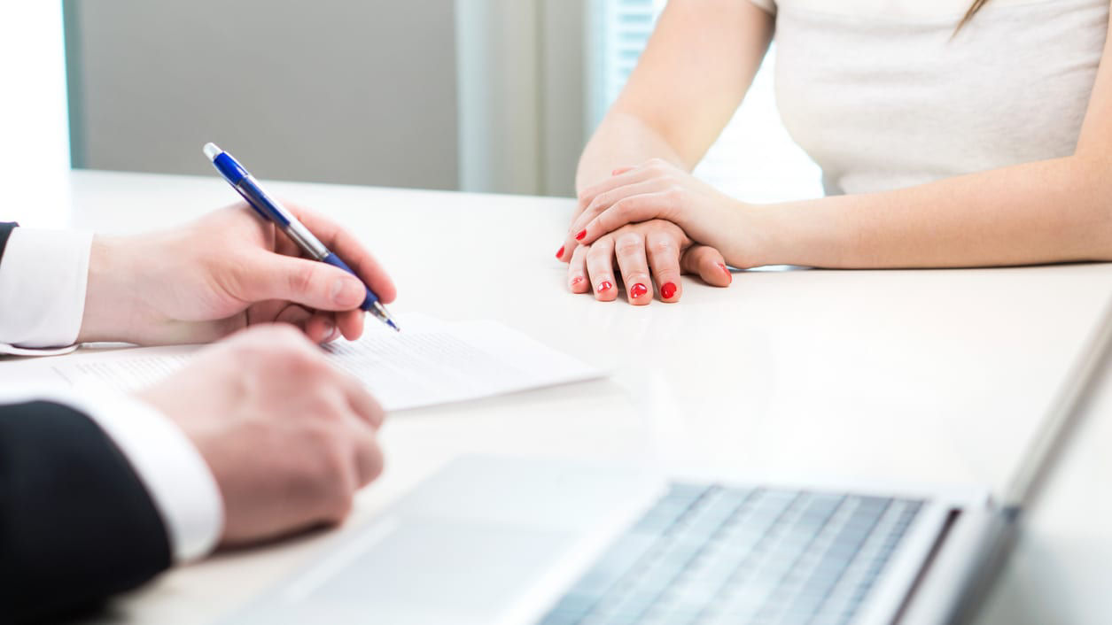 A man and woman are sitting at a desk in an office.