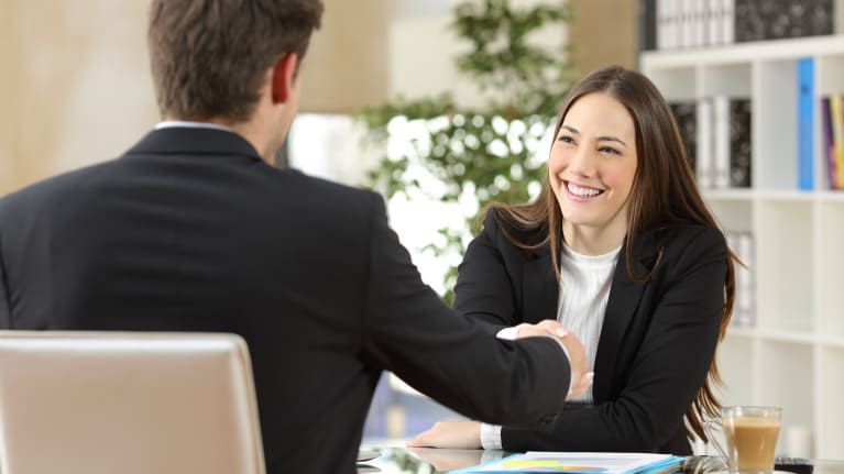 A man and woman shaking hands in an office.