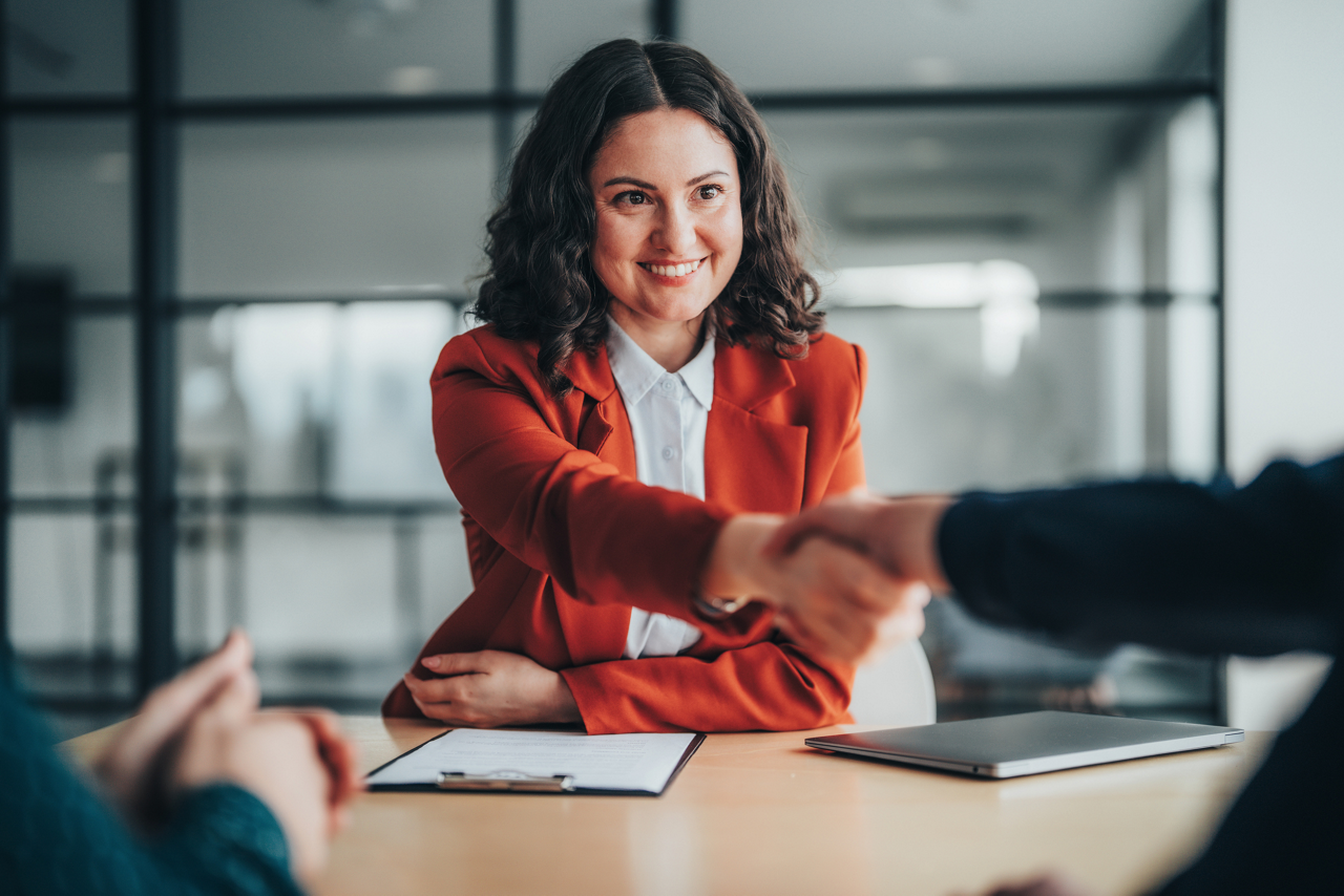 Professional real estate agent meets with clients to finalize a property deal in a modern office environment. The scene highlights negotiation, trust, and successful agreement, representing home buying, property investment, and client-focused real estate services