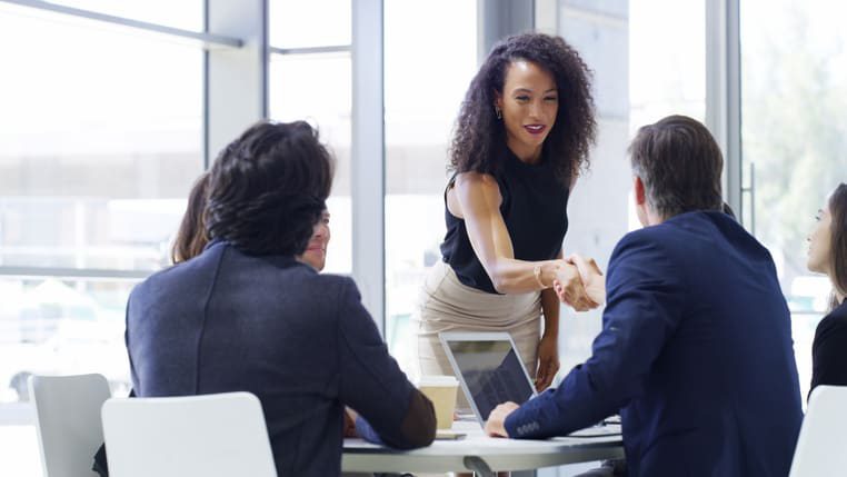 A group of business people shaking hands at a meeting.