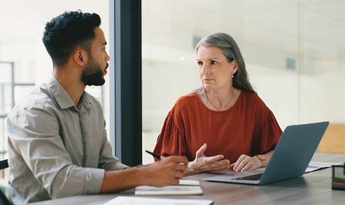 Collaboration of young businessman and senior woman in partnership in discussion or talking in office. Teamwork, project and diverse people working together for company or startup growth strategy