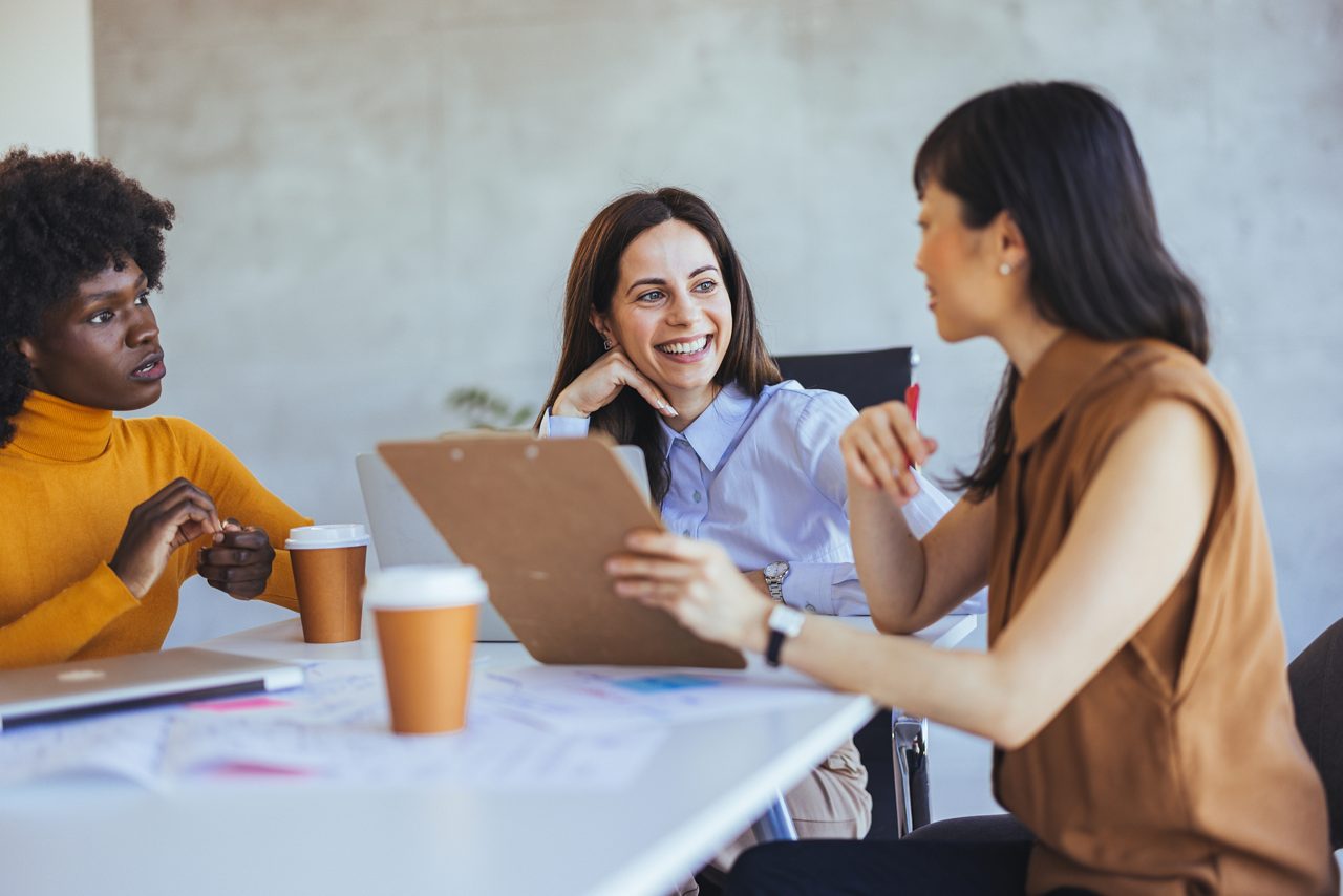 Three women in a conference room.