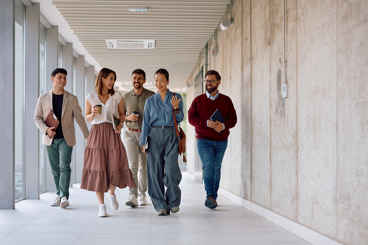 Happy business team walking in a hallway of an office building. Focus is on businesswomen talking.