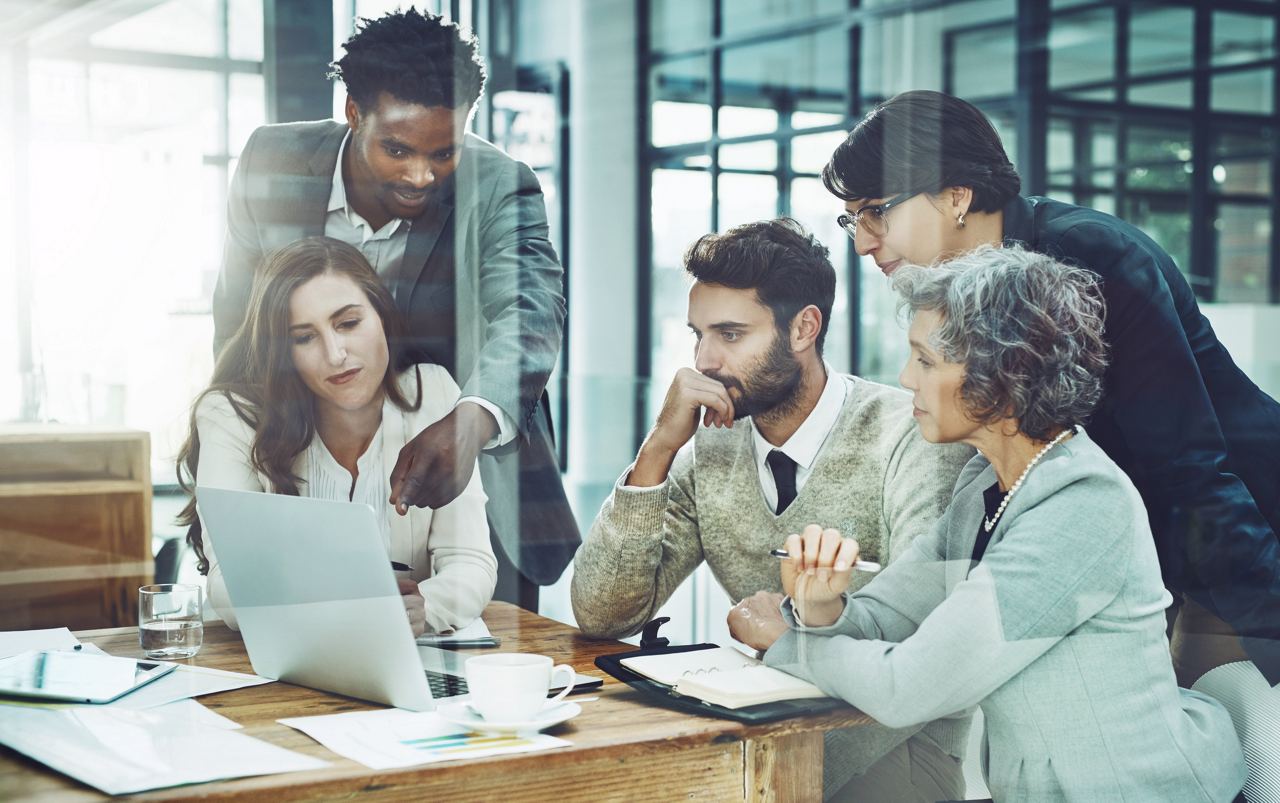 Shot of a cheerful motivated group of businesspeople having a discussion over a laptop in the office