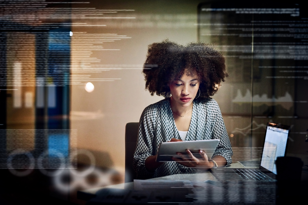 Shot of a young female programmer using a digital tablet while working late in her office