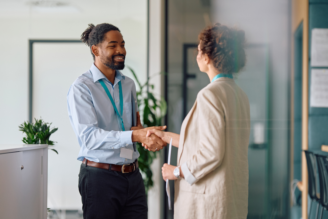 Job candidate and interviewer shake hands in an office hallway