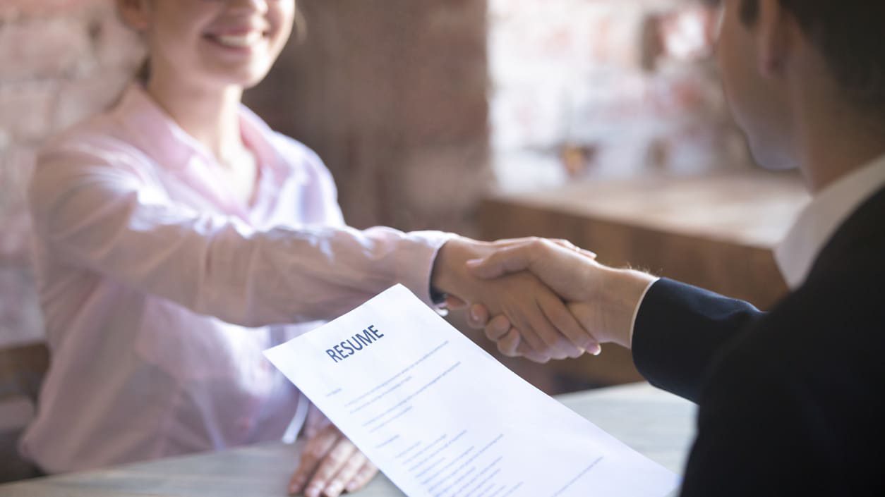 A woman shaking hands with a man at a table.