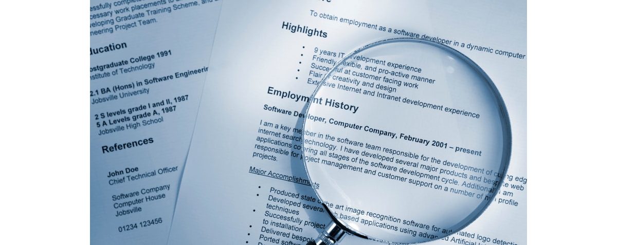 A magnifying glass is placed on top of a resume.