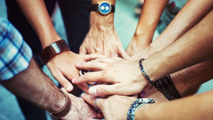 A group of people putting their hands together in a circle.