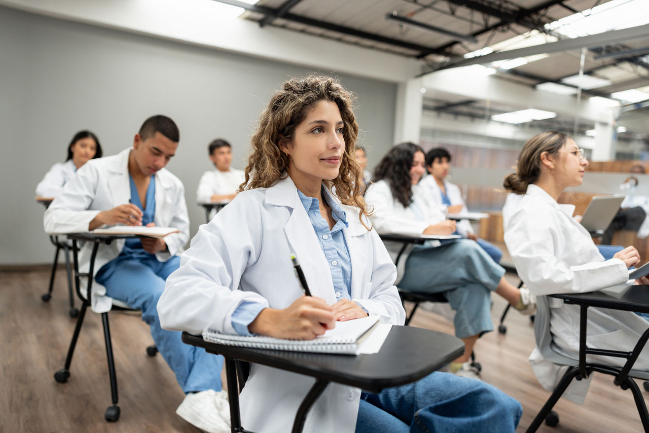 Group of Latin American medical students sitting in the classroom listening to a lecture and taking notes - medical school concepts