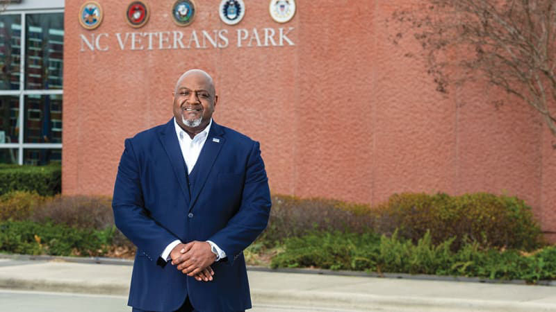 A man in a suit standing in front of a brick building.