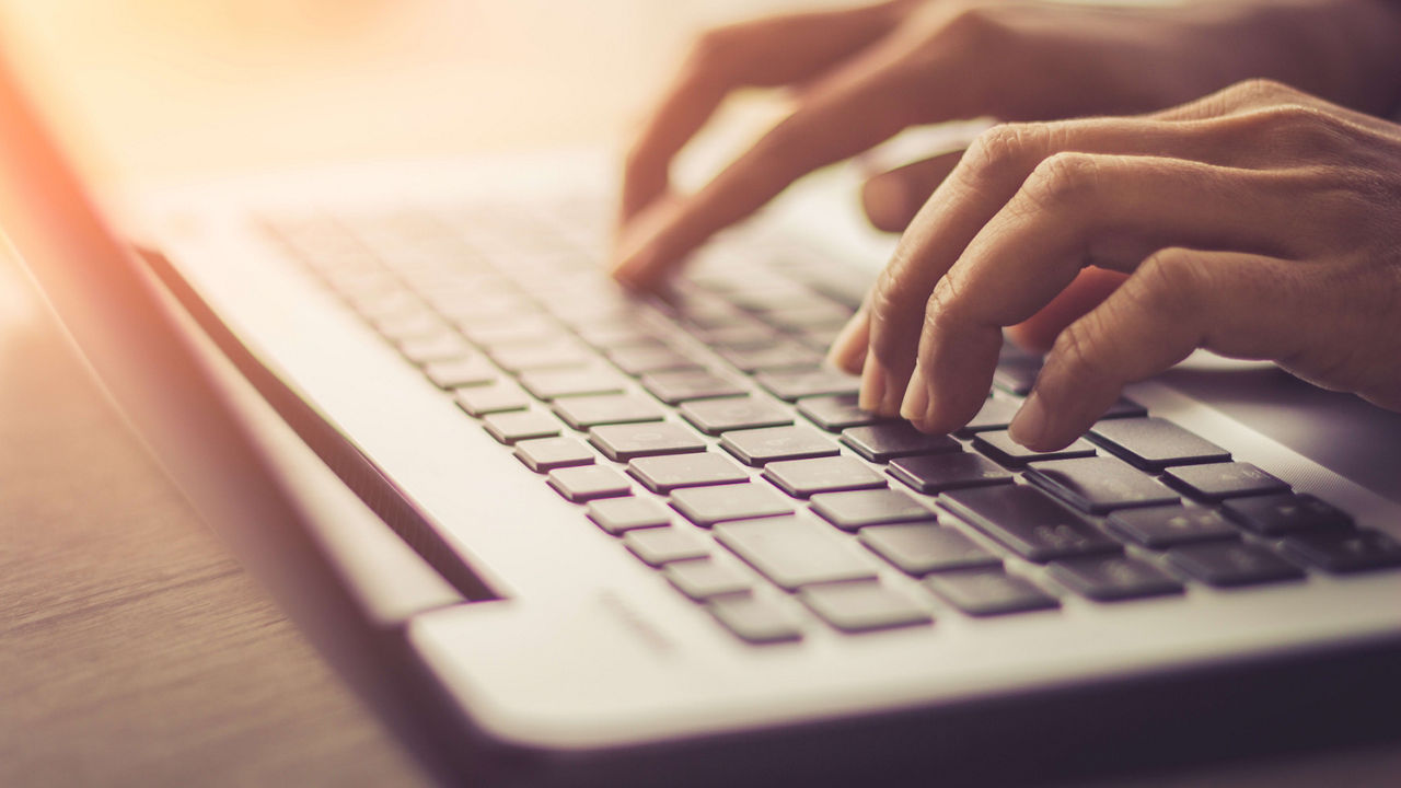 A person typing on a laptop keyboard.