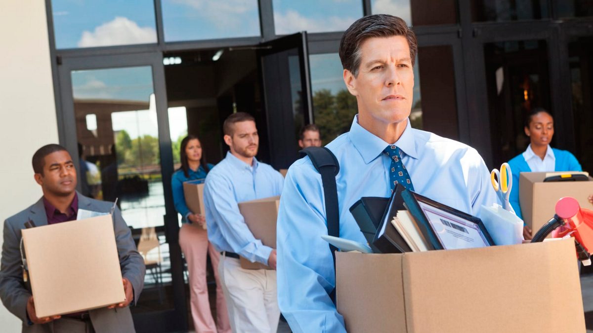 Workers leaving an office with boxes of their belongings
